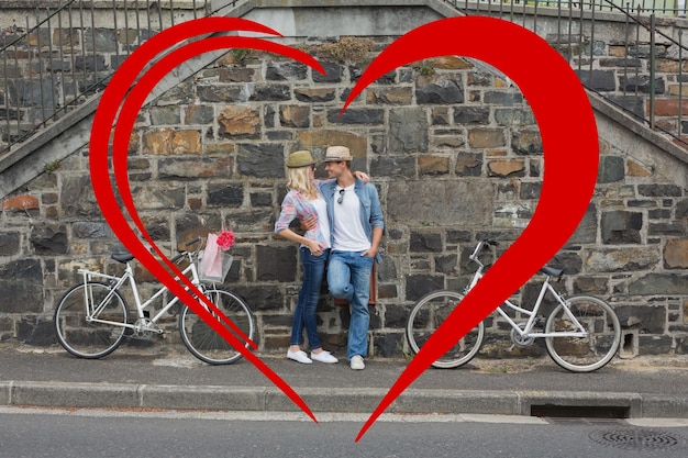 Anca giovane coppia in piedi accanto a un muro di mattoni con le loro biciclette contro il cuore