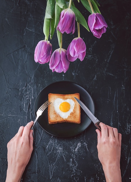 Ancora colazione per una persona cara con i tulipani su uno sfondo scuro