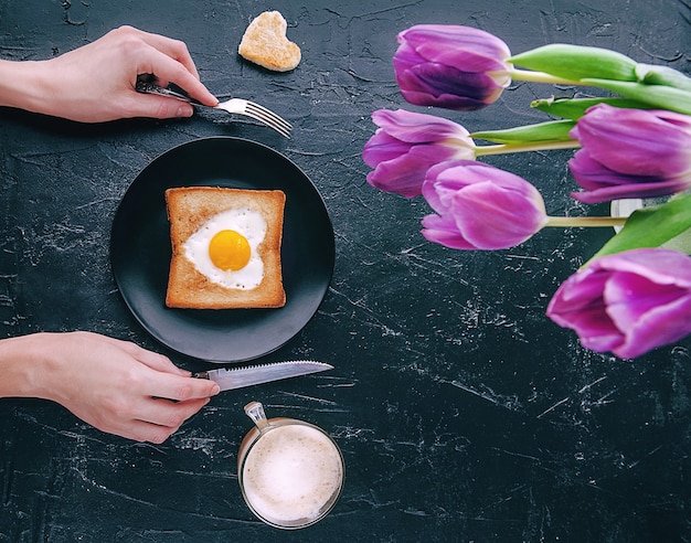 Ancora colazione per una persona cara con i tulipani su uno sfondo scuro