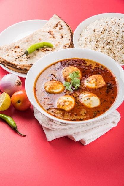 Anda Curry o sugo di masala di uova, cibo piccante indiano o ricetta, servito con riso Jeera, roti o naan, fuoco selettivo. Sopra il piano del tavolo colorato o in legno