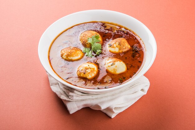 Anda Curry o sugo di masala di uova, cibo piccante indiano o ricetta, servito con riso Jeera, roti o naan, fuoco selettivo. Sopra il piano del tavolo colorato o in legno