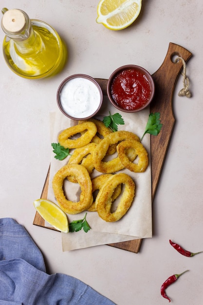 Anelli di calamari fritti con due salse, limone ed erbe aromatiche. Fast food. Aperitivo.