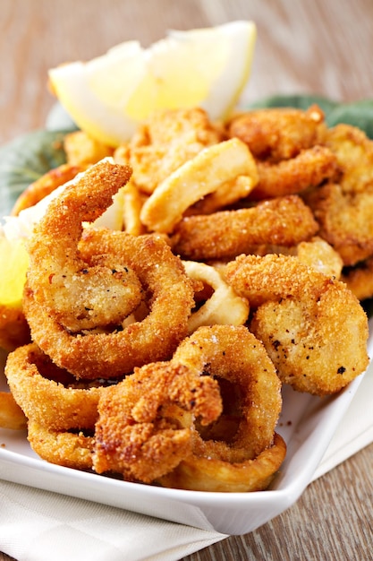 Anelli di calamari fritti impanati con limone su un piatto