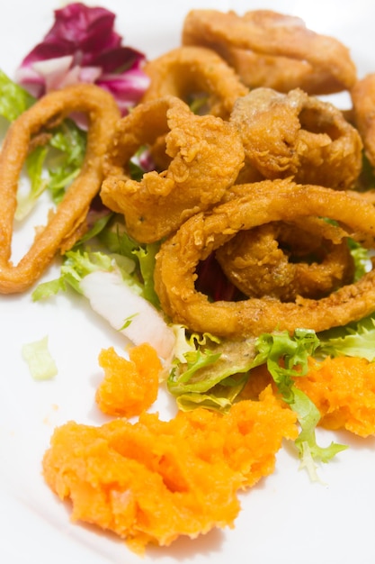 Anelli di calamari serviti con una varietà di lattuga e condimento aromatico di frutta.