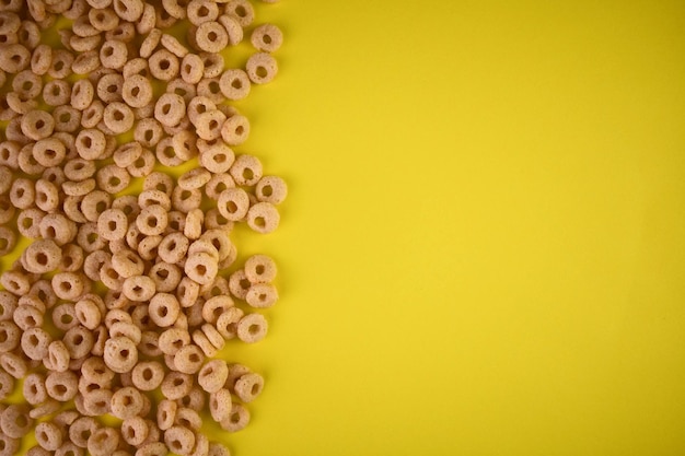 Anelli di cereali per colazione con latte su sfondo giallo.Copia spazio.