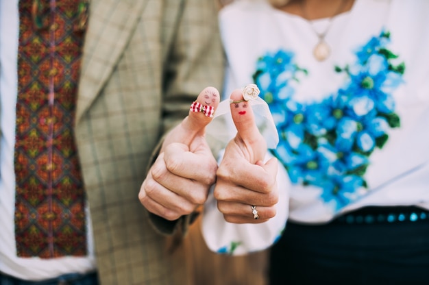 anelli di nozze sulle dita dipinte con la sposa e lo sposo, piccoli uomini divertenti