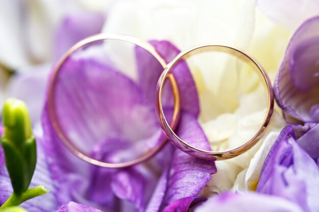 Anelli nuziali d'oro su un bouquet di fiori per la sposa