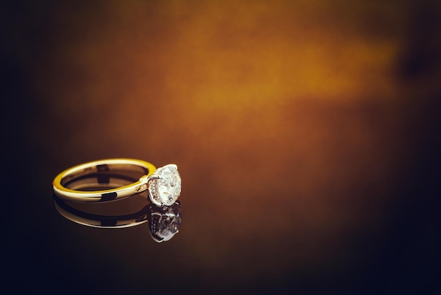 Anello di diamanti su sfondo bokeh chiaro dorato