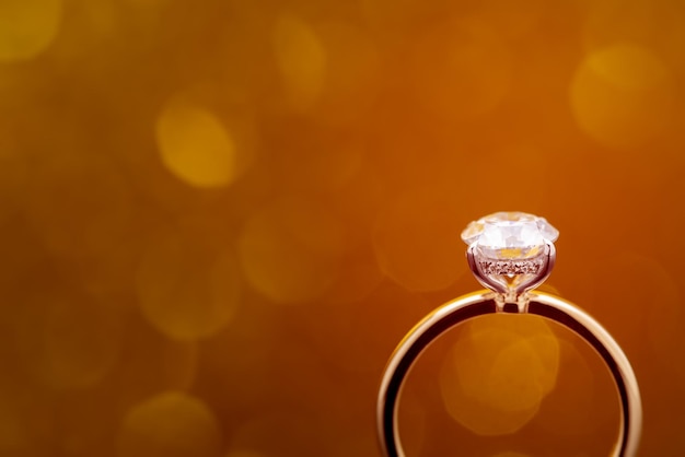 Anello di diamanti su sfondo bokeh chiaro dorato