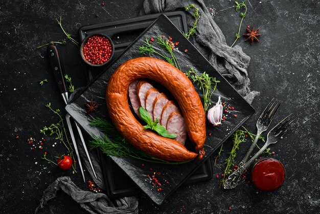 Anello di salame con rosmarino fresco e spezie su fondo di pietra nera Vista dall'alto Spazio libero per il testo