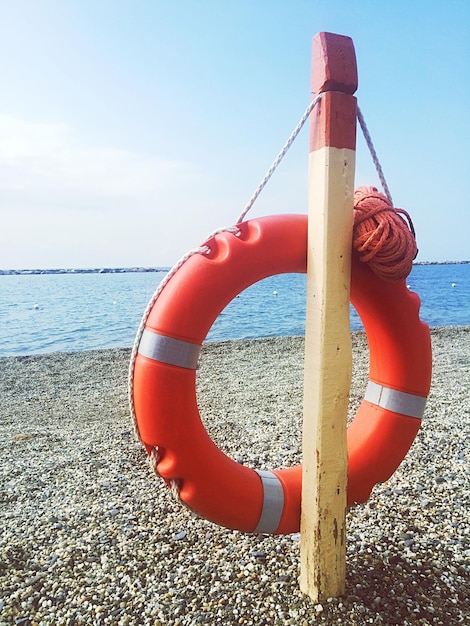 Anello di salvataggio appeso a un palo di legno sulla spiaggia contro il cielo