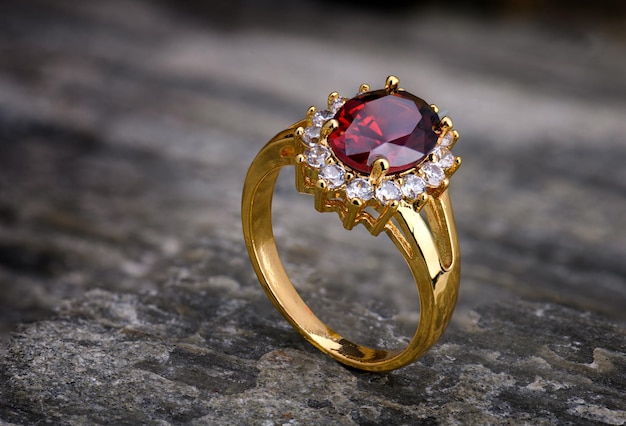 Anello dorato di gioielli in pietre preziose con struttura in pietra naturale nell'illuminazione da studio.