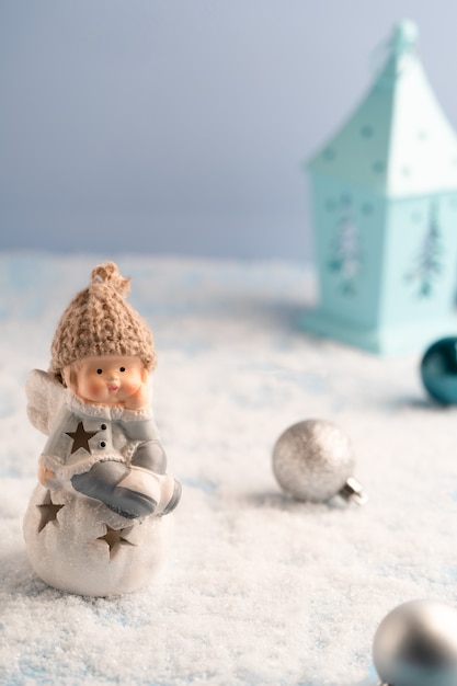 Angelo carino, lanterna blu e decorazioni natalizie nella neve, cartolina di Natale. Foto di alta qualità