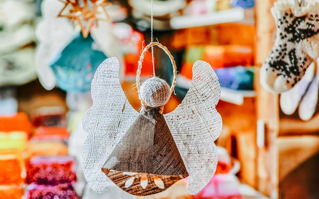 Angelo di lino fatto a mano appeso al mercatino di Natale nella vecchia Riga, Lettonia. L'Europa in inverno. Street Xmas e fiera delle vacanze. Decorazione dell'Avvento e bancarelle con oggetti di artigianato su Bazaar