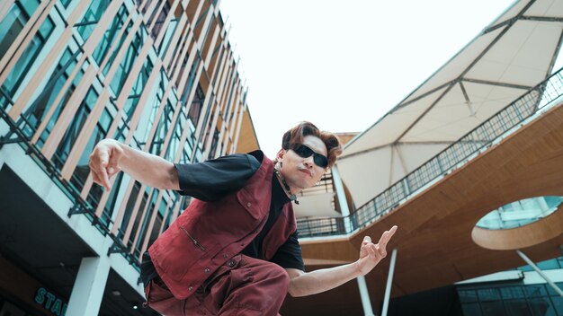 Angolo basso di asiatica attraente hipster posa alla telecamera circondato da mall sforzo
