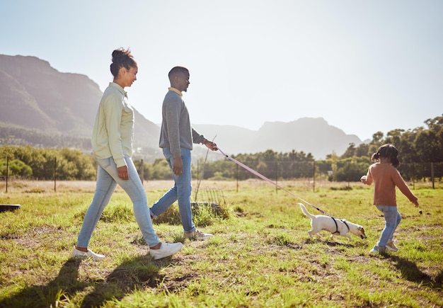 Animale domestico della natura e famiglia nera che fanno una passeggiata con il cane divertendosi a legare e godersi l'estate Ama gli animali e mamma e papà che camminano con la ragazza e il cucciolo nel parco durante le vacanze e le vacanze del fine settimana