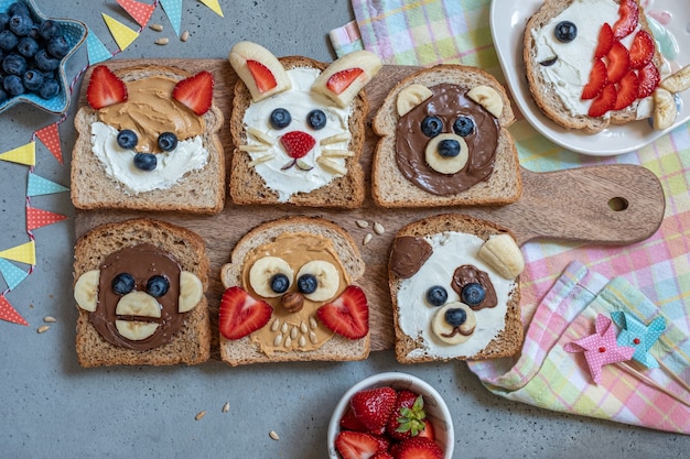 Animali divertenti facce toast con burro, banana, fragola e mirtillo