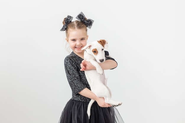Animali domestici e concetto di animali - Ragazza del bambino che gioca con il cucciolo Jack Russell Terrier.