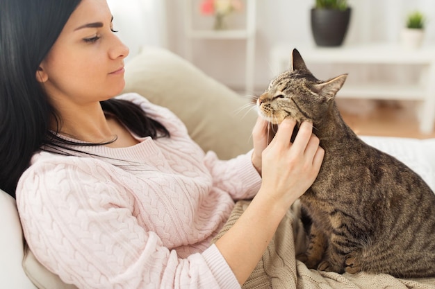 animali domestici hygge e persone concetto ravvicinato di donna con gatto tabby a letto a casa