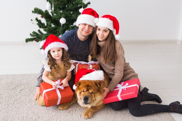 Animali domestici, vacanze e concetto festivo - La famiglia con il cane è sdraiata sul pavimento vicino all'albero di natale.