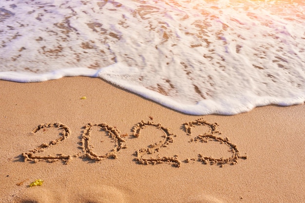 Anno 2023 scritto sul mare della spiaggia sabbiosa in una giornata di sole