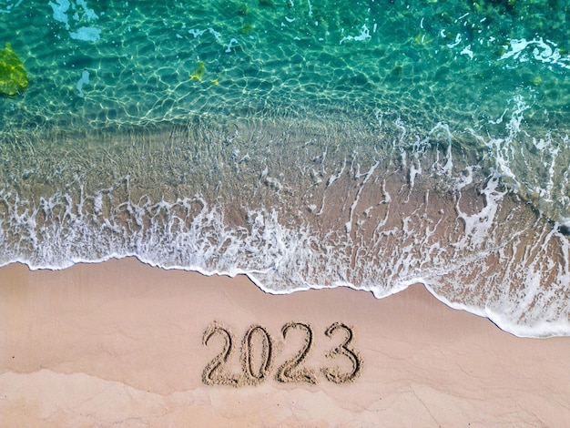 Anno 2023 scritto sul mare della spiaggia sabbiosa in una giornata di sole