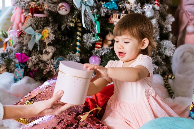 Anno nuovo buon natale buone feste ritratto di bambina in abito rosa si siede sul pavimento con pil...