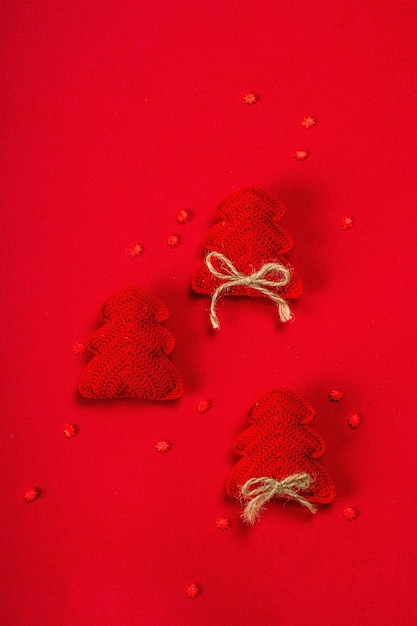 Anno nuovo o sfondo di Natale. Abete all'uncinetto fatto a mano, fiocchi di neve dolci su fondo ruvido rosso. Design minimalista monocromatico, disposizione piatta