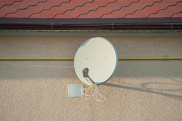 Antenna tv satellitare sul muro della casa in una giornata estiva