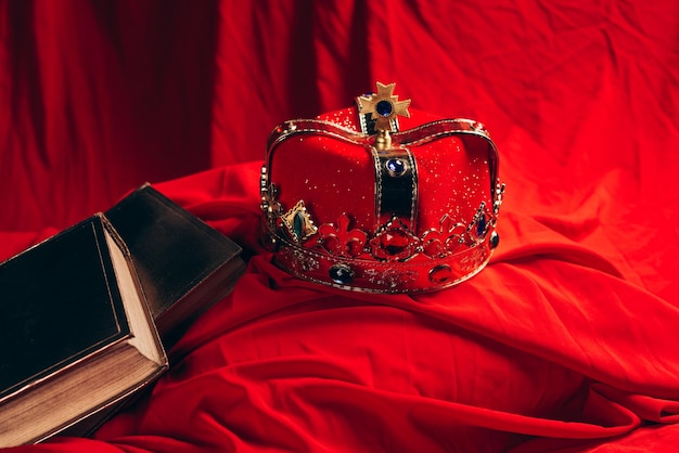 Antica corona d'oro con pietre preziose su panno rosso con libri