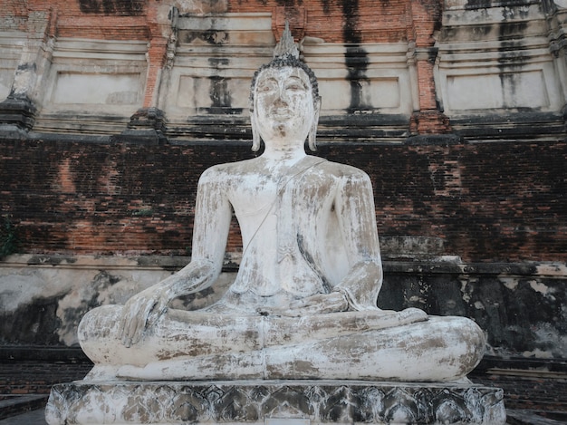 Antica statua del Buddha bianco antico con sfondo a parete pagoda in Wat Yai Chai Mongkhon tempio buddista nella provincia di Phra Nakhon Si Ayutthaya, Thailandia