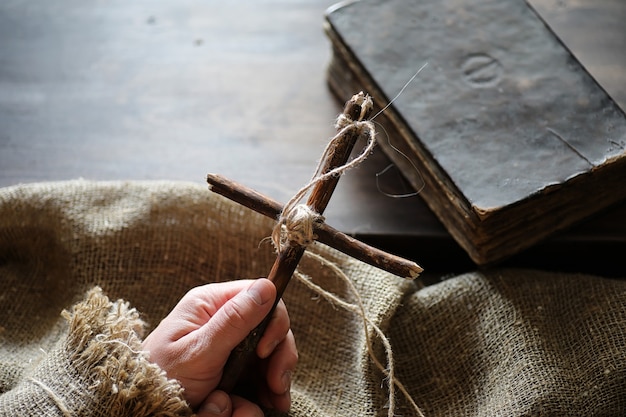 Antico libro religioso e croce di legno sullo sfondo di un legno e tela