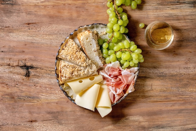 Antipasti Antipasti con focaccia bianca siciliana. Torta a fette di pane tradizionale con cipolla servita con prosciutto, formaggio, uva e bicchiere di vino bianco