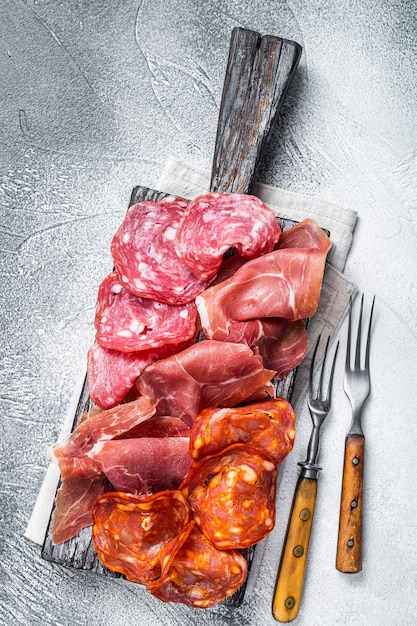 Antipasti di carne assortiti - salame, prosciutto, salsicce choriso. Tavolo bianco. Vista dall'alto.