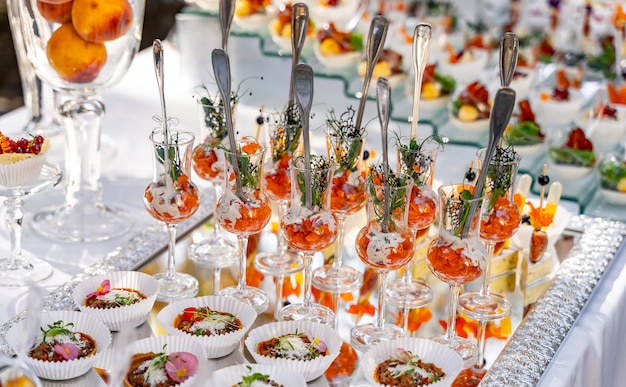 Antipasti in bicchierini sul tavolo bianco sfondo sfocato. Tavolo da festa. Concetto di ristorazione.