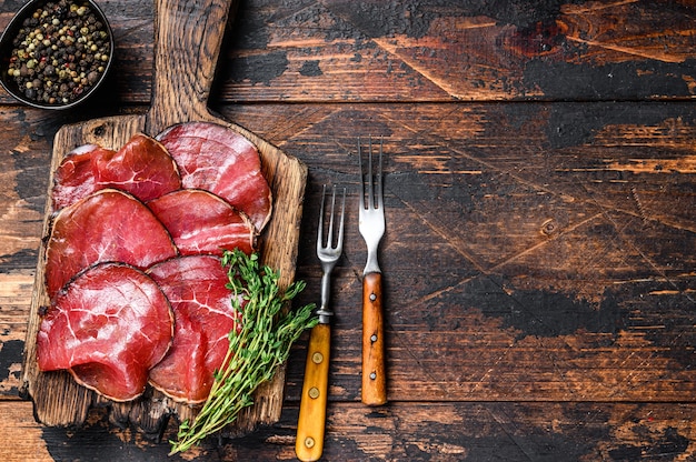 Antipasti Italiani Bresaola tagliata di manzo a pezzi. Fondo in legno scuro.