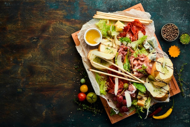 Antipasto Cibo italiano Prosciutto capperi salame parmigiano miele su tavola di legno Vista dall'alto Stile rustico