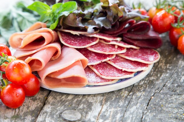 Antipasto con prosciutto, salame e bresaola. pomodoro e basilico. messa a fuoco selettiva