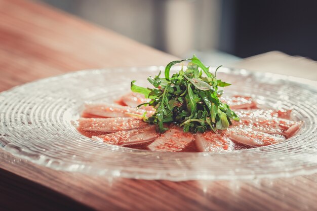 Antipasto delizioso con erbe su lastra di vetro su tavola di legno