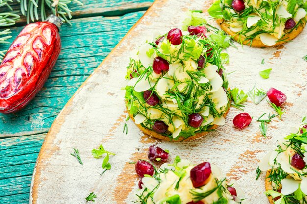 Antipasto delizioso per la tavola di Natale. Crostini con formaggio, aglio e melograno.