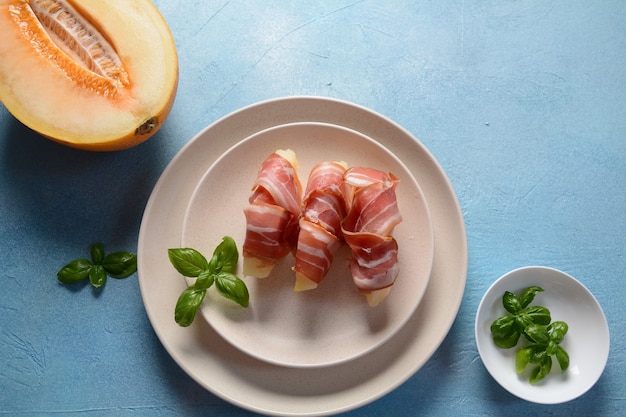 Antipasto estivo con melone dolce e prosciutto su sfondo blu