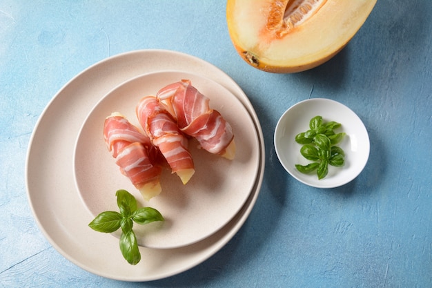 Antipasto estivo con melone dolce e prosciutto su sfondo blu