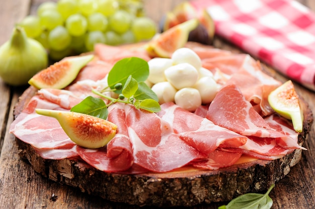 Antipasto, fichi e prosciutto su tavola di legno