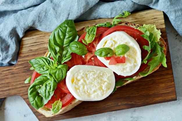 Antipasto italiano Bruschetta toast con insalata caprese su una tavola di legno su sfondo blu