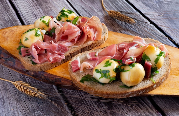 Antipasto spuntino con pane integrale, prosciutto crudo e polpettine di provola affumicata sott'olio