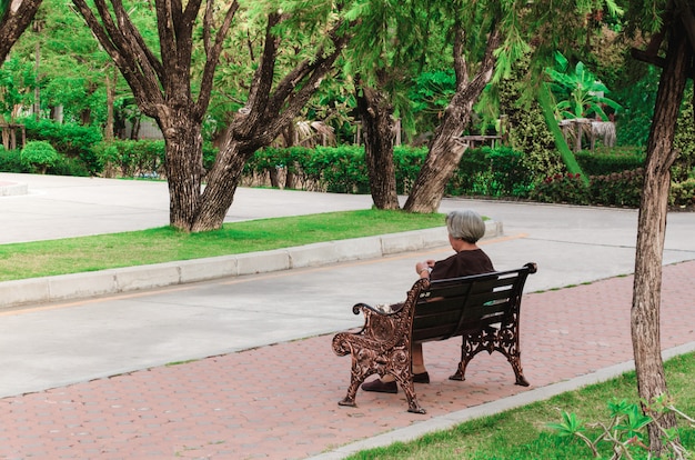 Anziana che si siede sulla panchina al parco