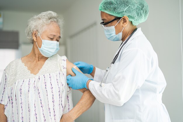 Anziana donna anziana asiatica che indossa una maschera facciale che riceve il vaccino contro il covid19 o il coronavirus
