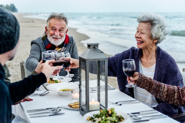 Anziani che tostano con vino rosso in spiaggia