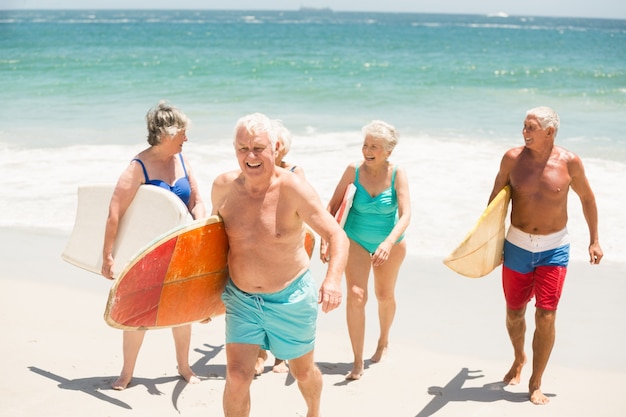 Anziani che trasportano tavole da surf in spiaggia
