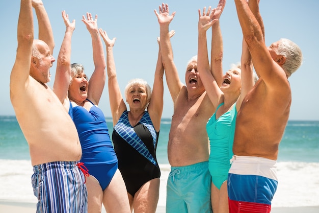 Anziani con le mani in alto in spiaggia